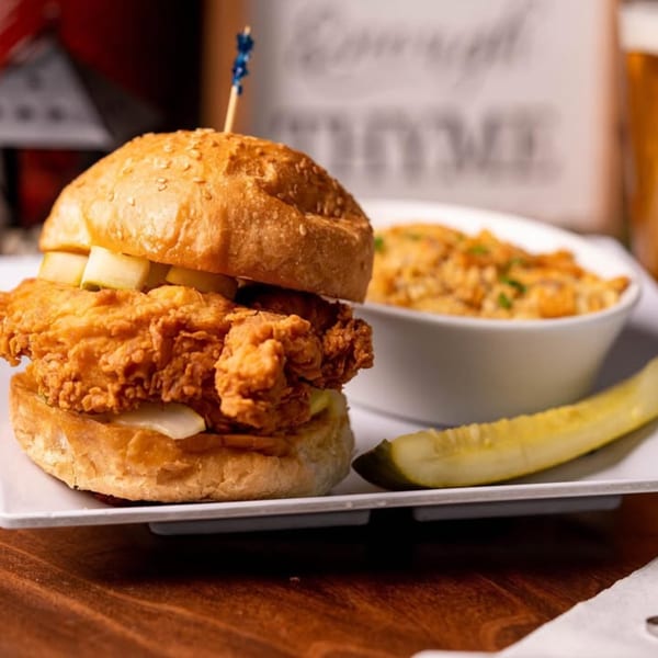 Crispy fried chicken sandwich with pickles, a side of mac and cheese, and a pickle spear.